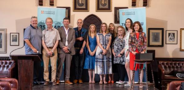 Group photo of staff standing in the debating chamber Cambridge staff at 25 Year Long Services Awards 2024