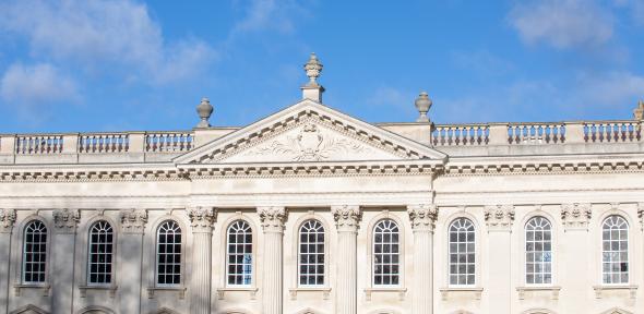 The image shows the upper part of the Senate House against a blue sky.