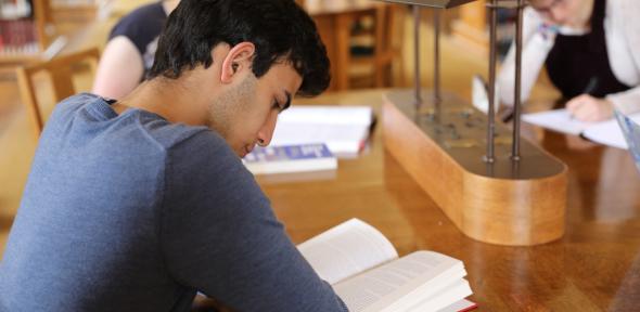 A student reads a book in a library